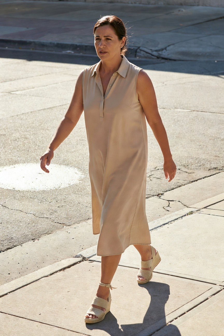 Woman walking on sidewalk in beige sleeveless collared midi shirt dress with matching strappy beige wedge espadrilles