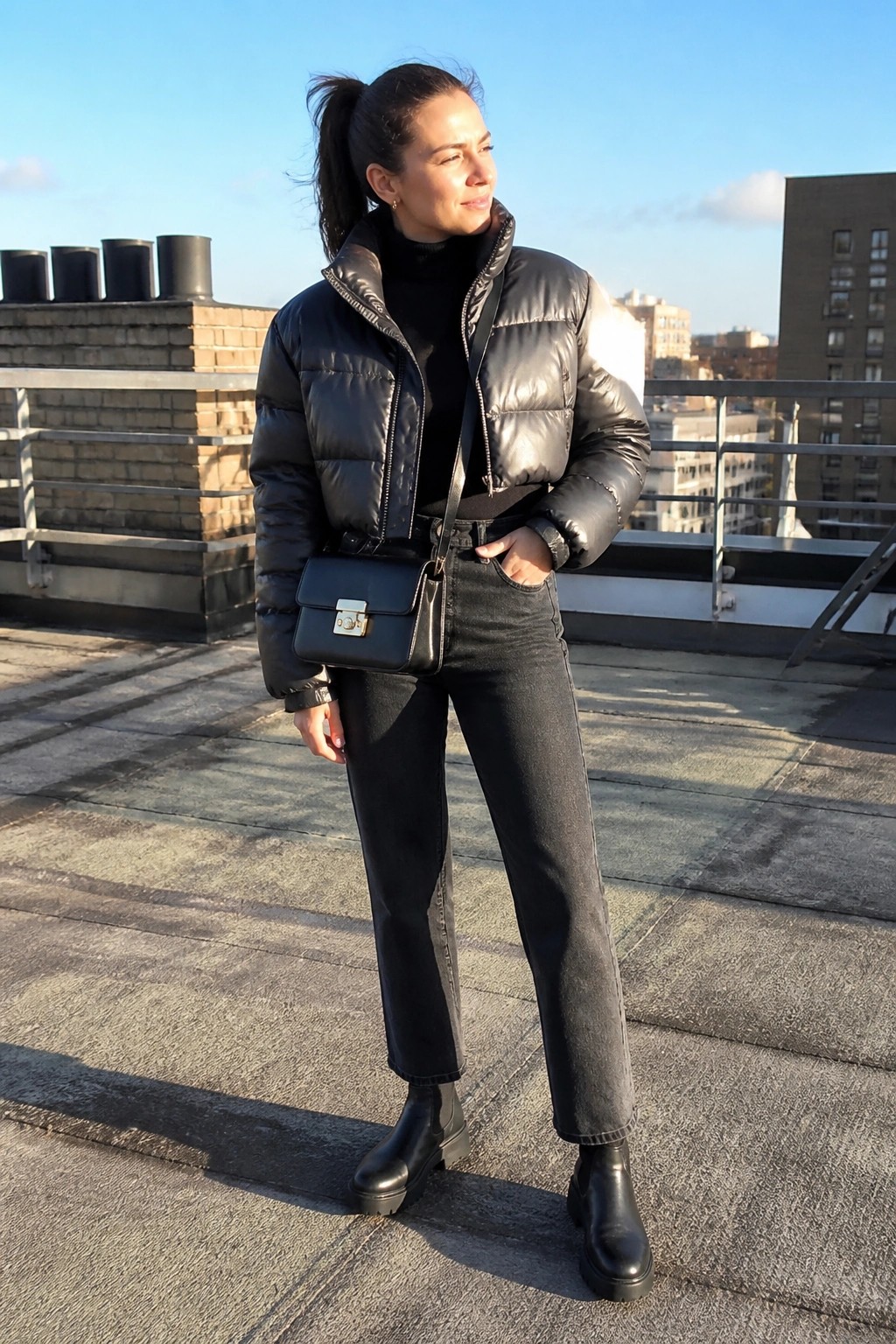 Woman in black puffer jacket and jeans on sunny city rooftop