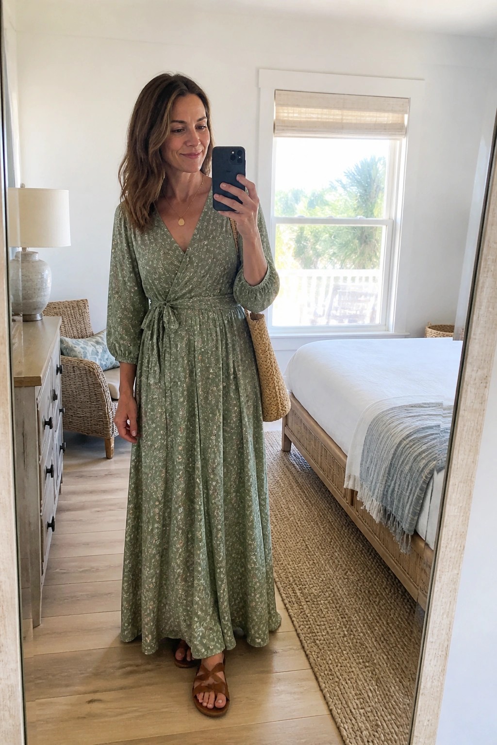 Woman in green floral maxi dress taking mirror selfie in bedroom