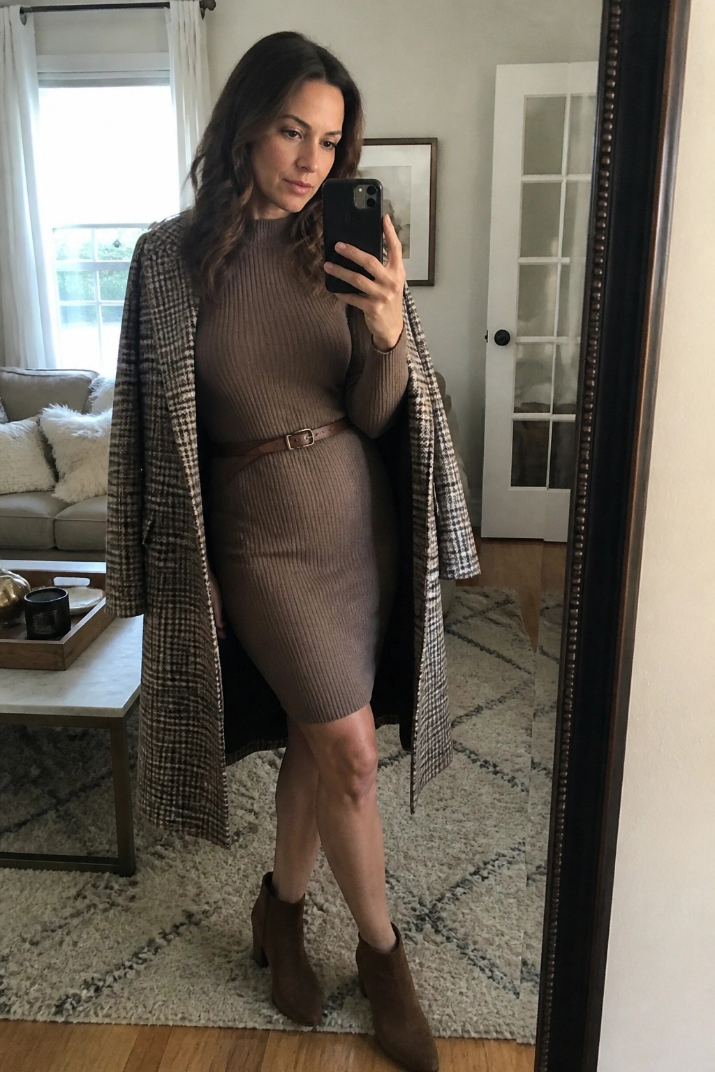 Woman in brown ribbed dress and houndstooth coat taking mirror selfie