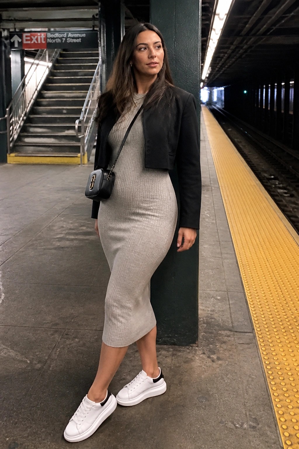 Woman in gray ribbed dress and black jacket on subway platform