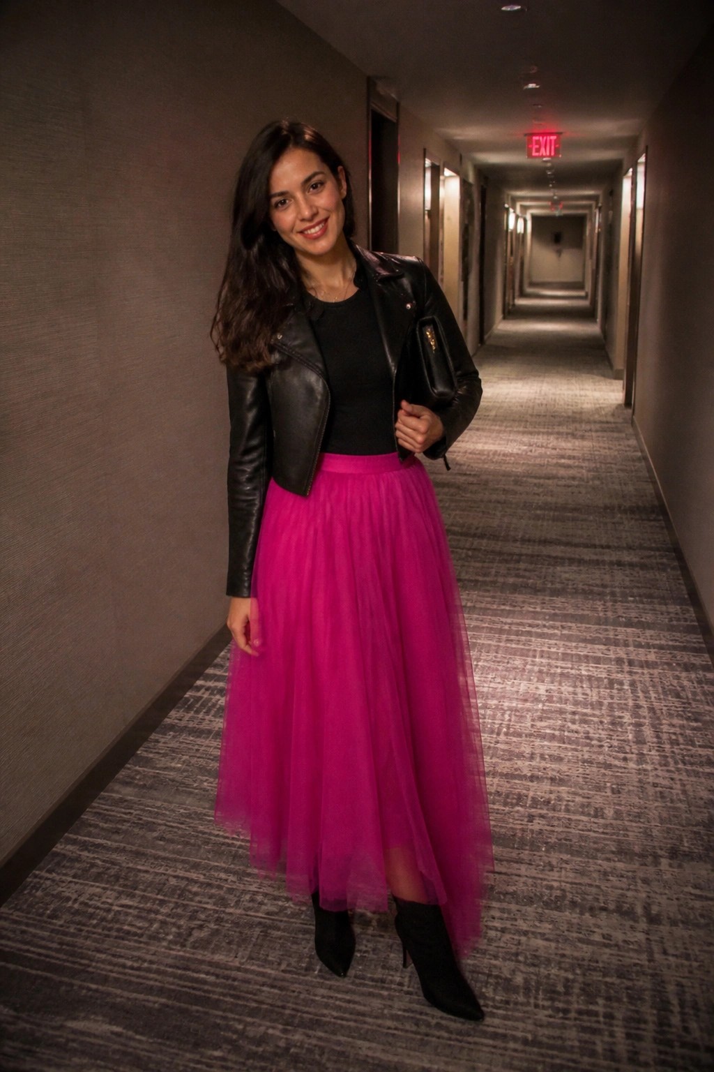 Woman in black leather jacket and bright pink tulle skirt in hallway