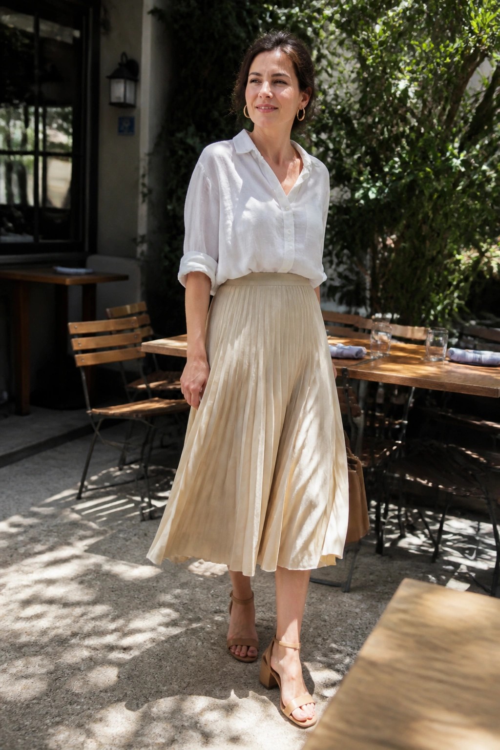 Woman in white shirt and beige pleated skirt on sunny outdoor cafe patio
