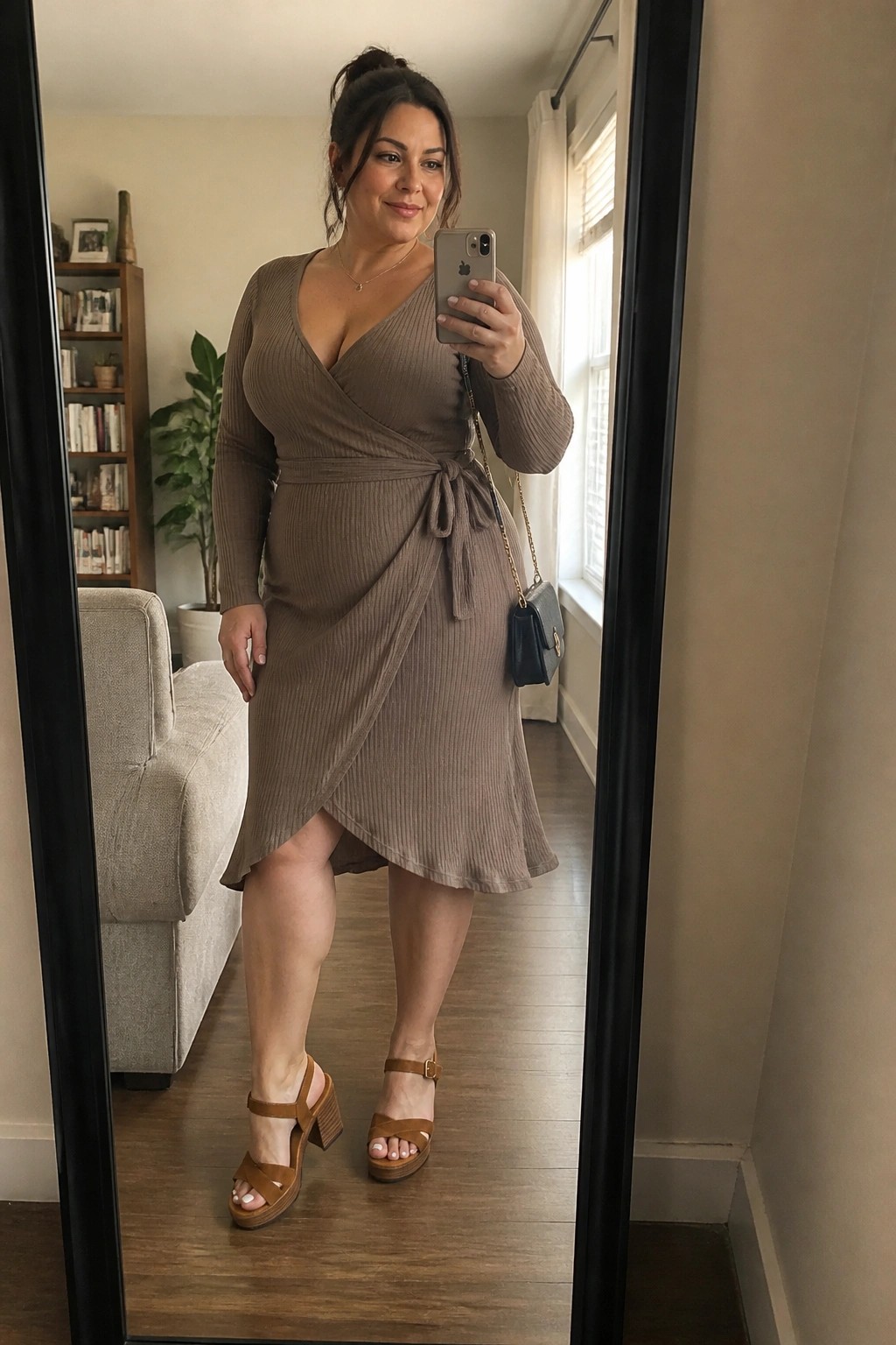 Woman in taupe ribbed wrap dress taking mirror selfie with phone
