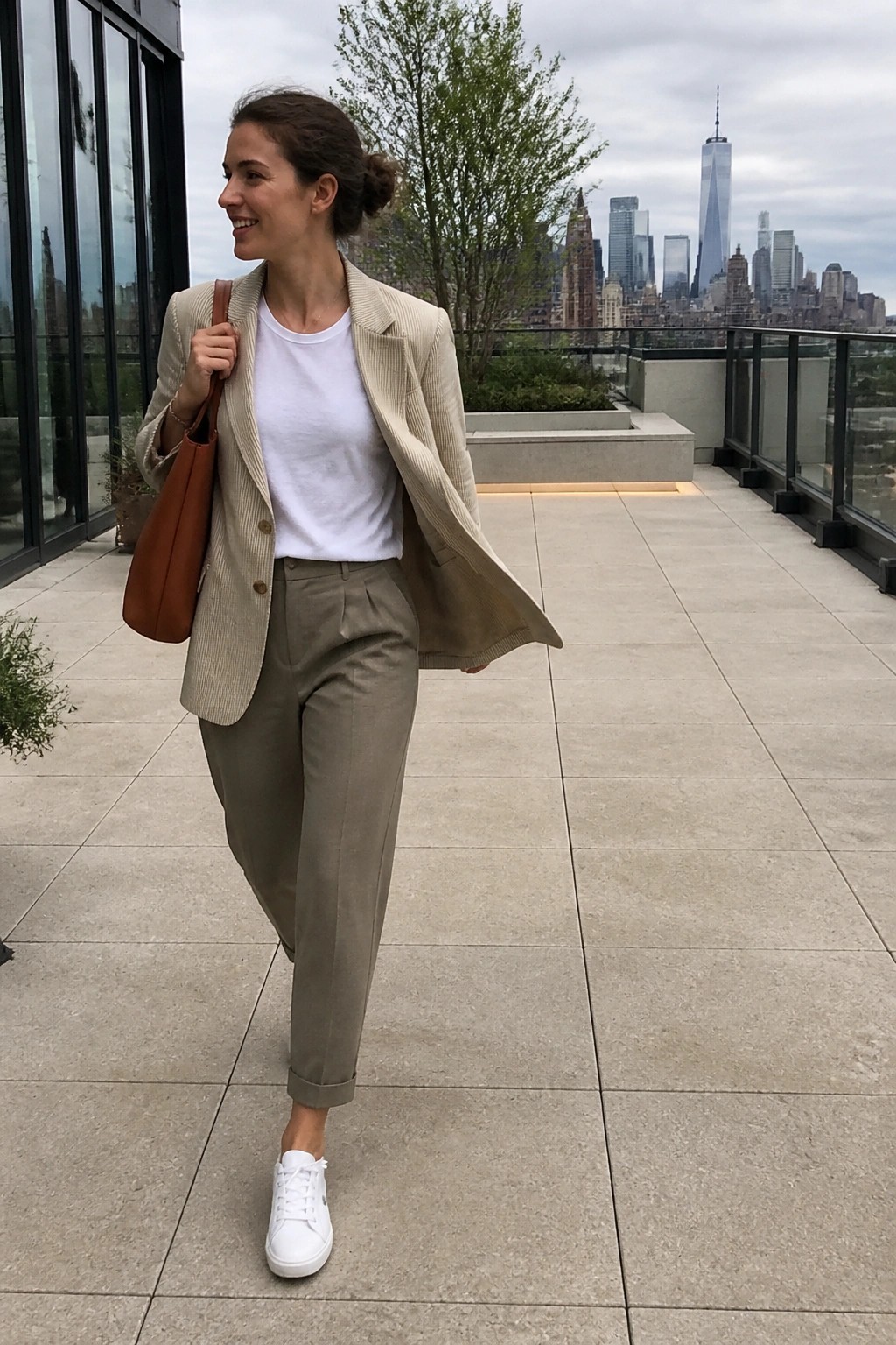 Woman in beige corduroy blazer and olive pants on NYC rooftop.