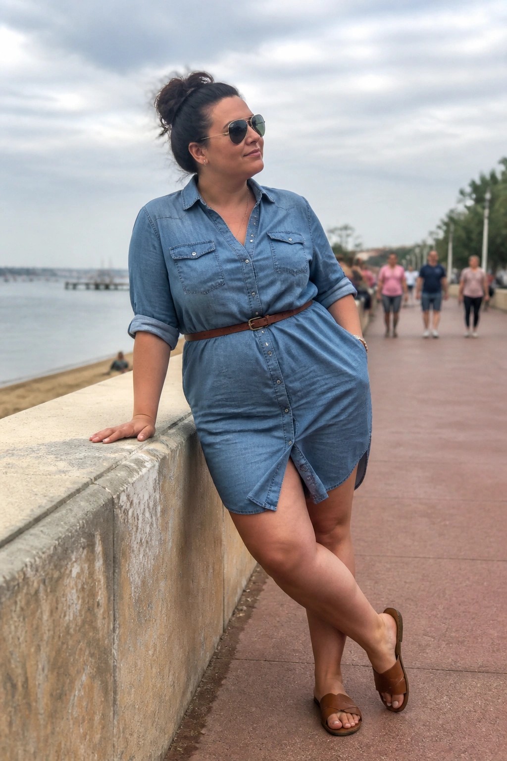 Woman in blue denim shirt dress with brown belt by the sea