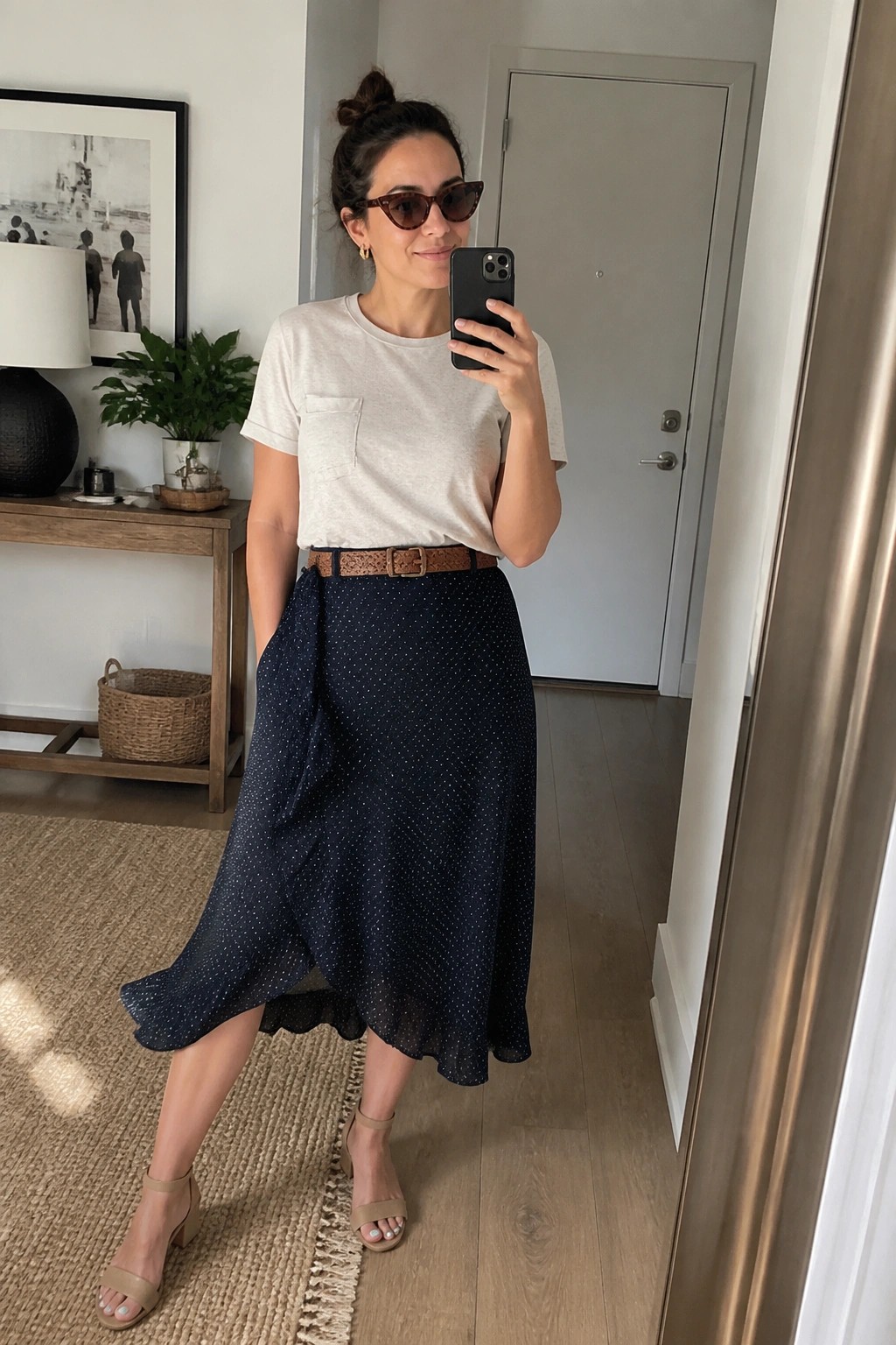 Woman in white tee and navy polka-dot skirt taking mirror selfie indoors