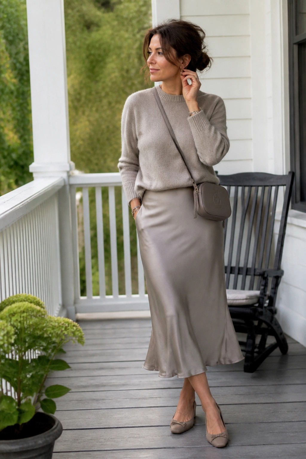 Woman in beige sweater and satin skirt on porch with rocking chair.