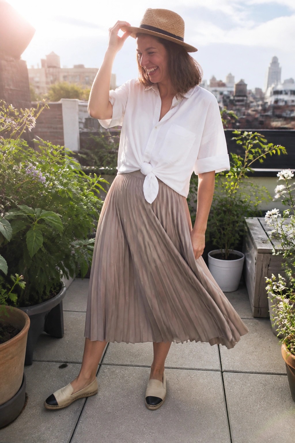 Woman in white tied shirt and pleated beige skirt on sunny rooftop with plants