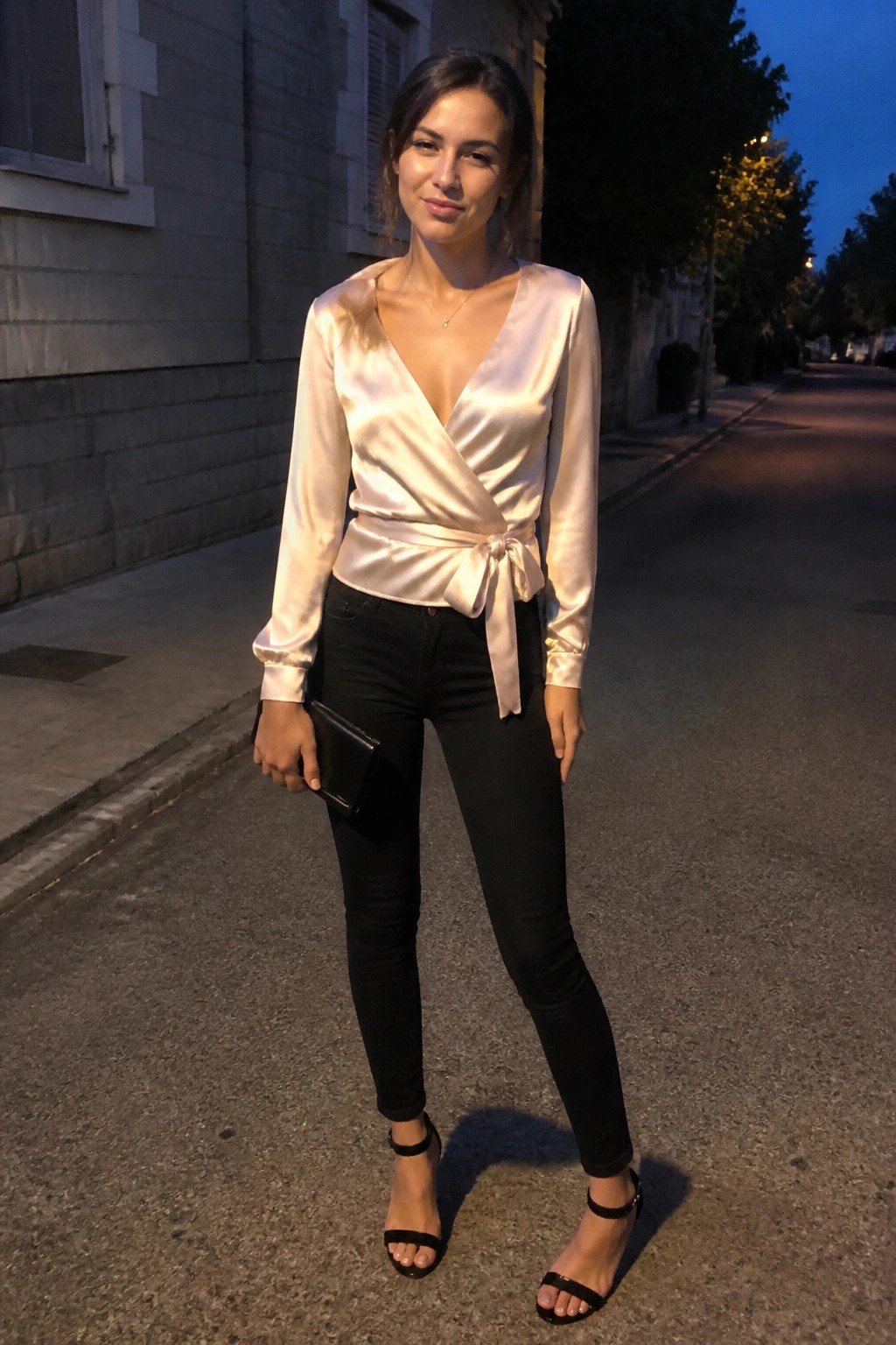 Woman in satin wrap blouse and black jeans on evening street