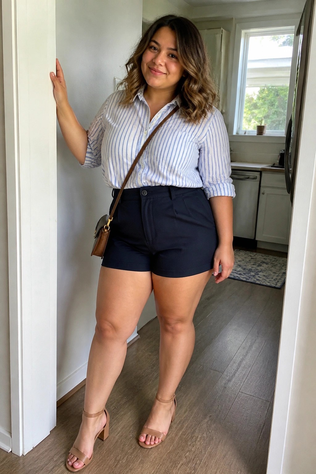 Woman in striped shirt and navy shorts leaning in kitchen doorway