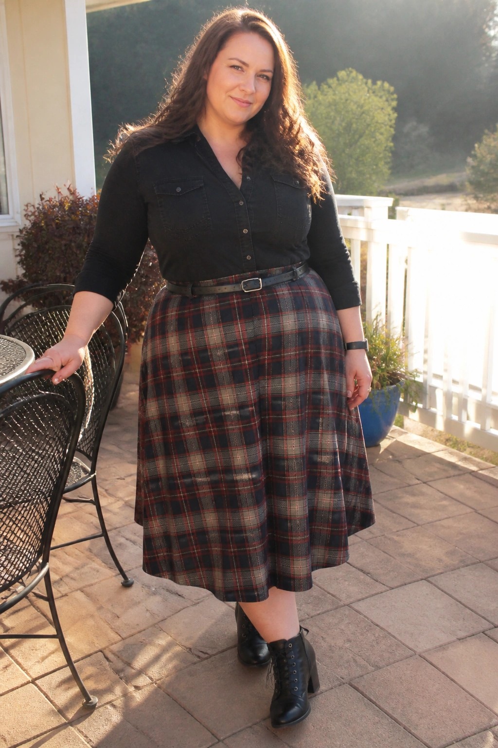 Woman in black shirt and red plaid skirt on sunlit wooden deck