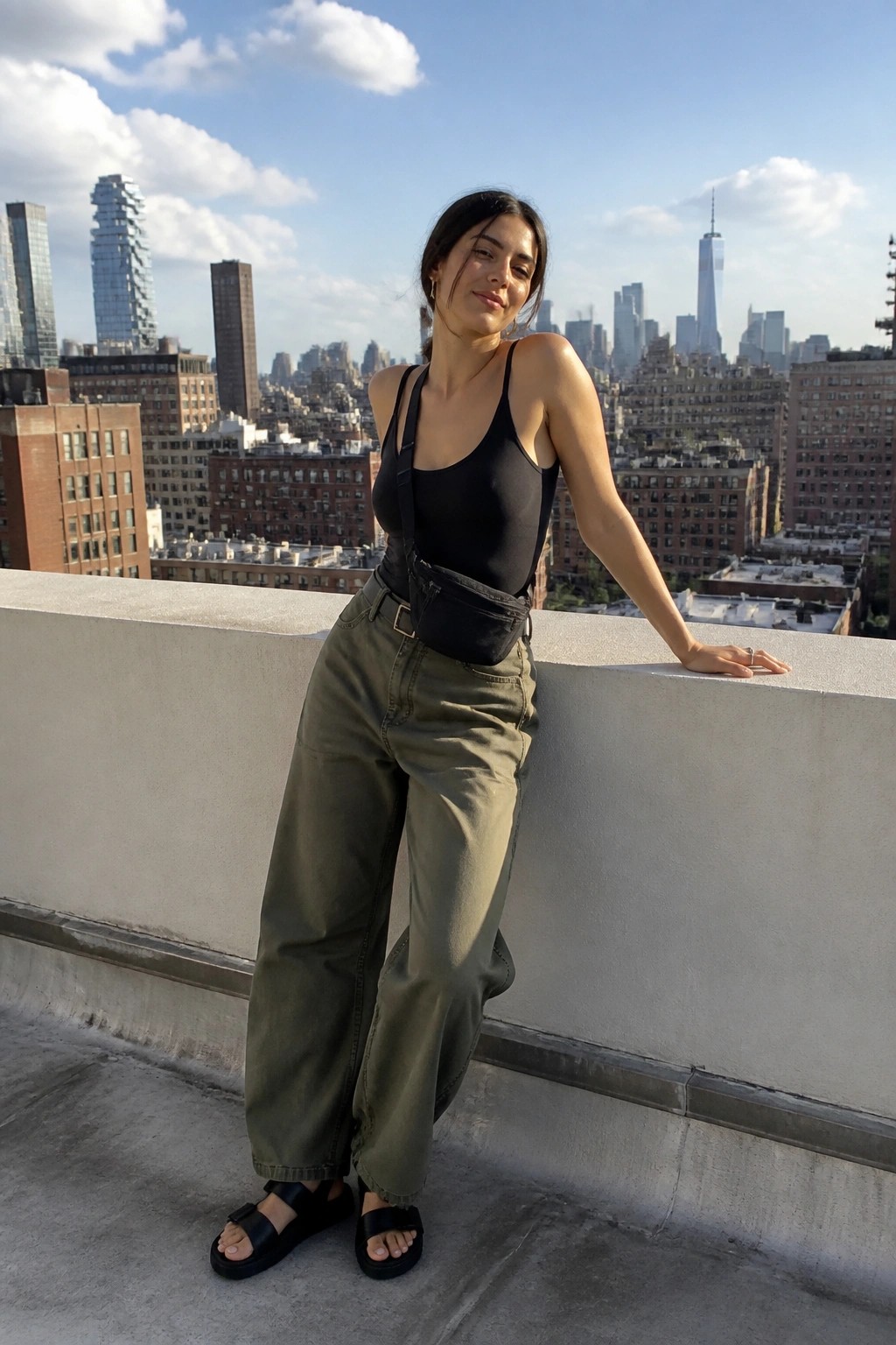 Woman in black bodysuit and olive cargo pants on NYC rooftop ledge