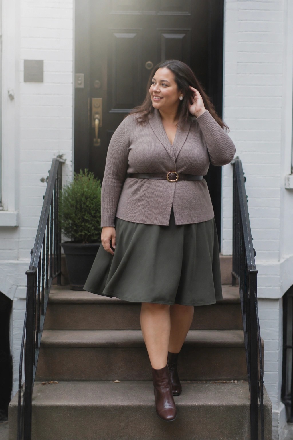 Woman in taupe cardigan and green skirt standing on outdoor steps