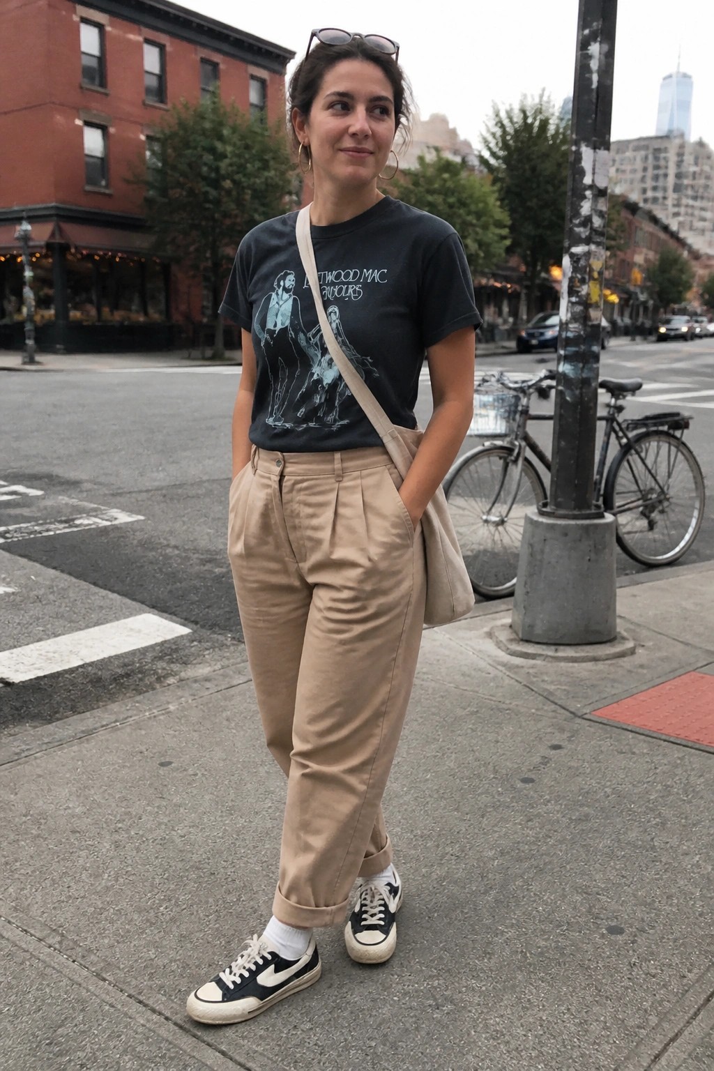 Woman in black Fleetwood Mac tee and beige pants on city sidewalk
