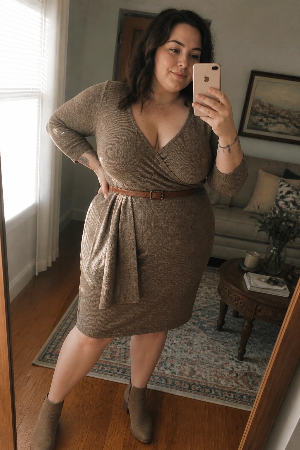 Woman in brown sparkly wrap dress taking mirror selfie in living room