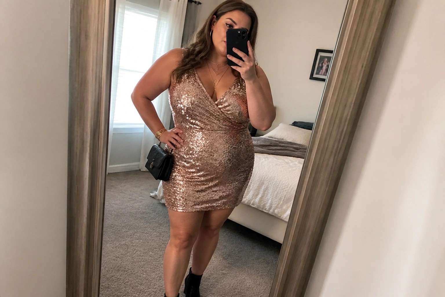 Woman in rose gold sequin mini dress and black ankle boots taking mirror selfie