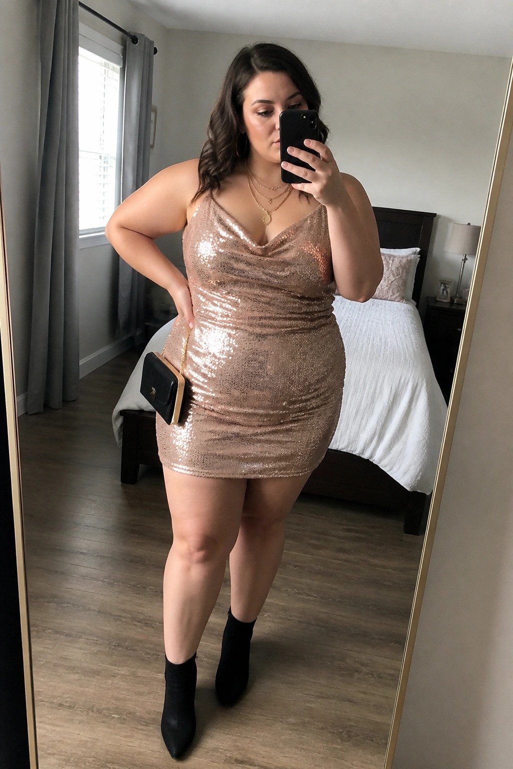 Woman in rose gold sequin mini dress and black ankle boots taking mirror selfie