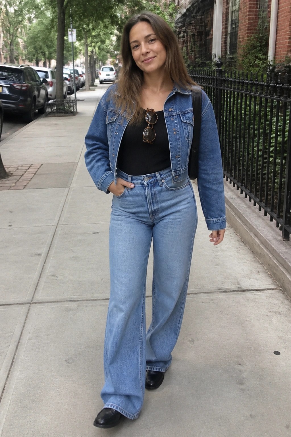Woman in blue denim jacket and wide-leg jeans on urban sidewalk