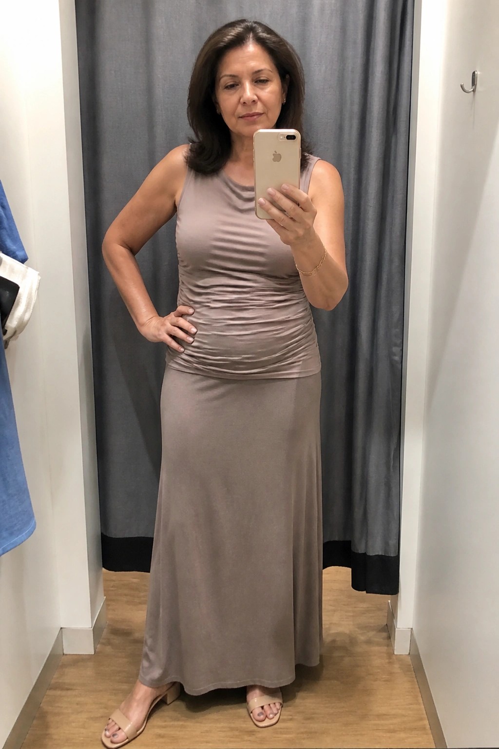 Woman in taupe ruched maxi dress taking mirror selfie in fitting room