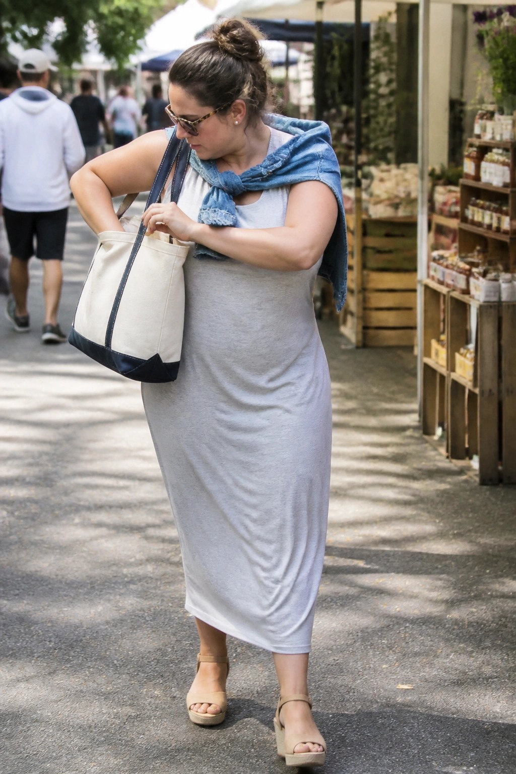 Woman in gray maxi dress with denim jacket and canvas tote at market