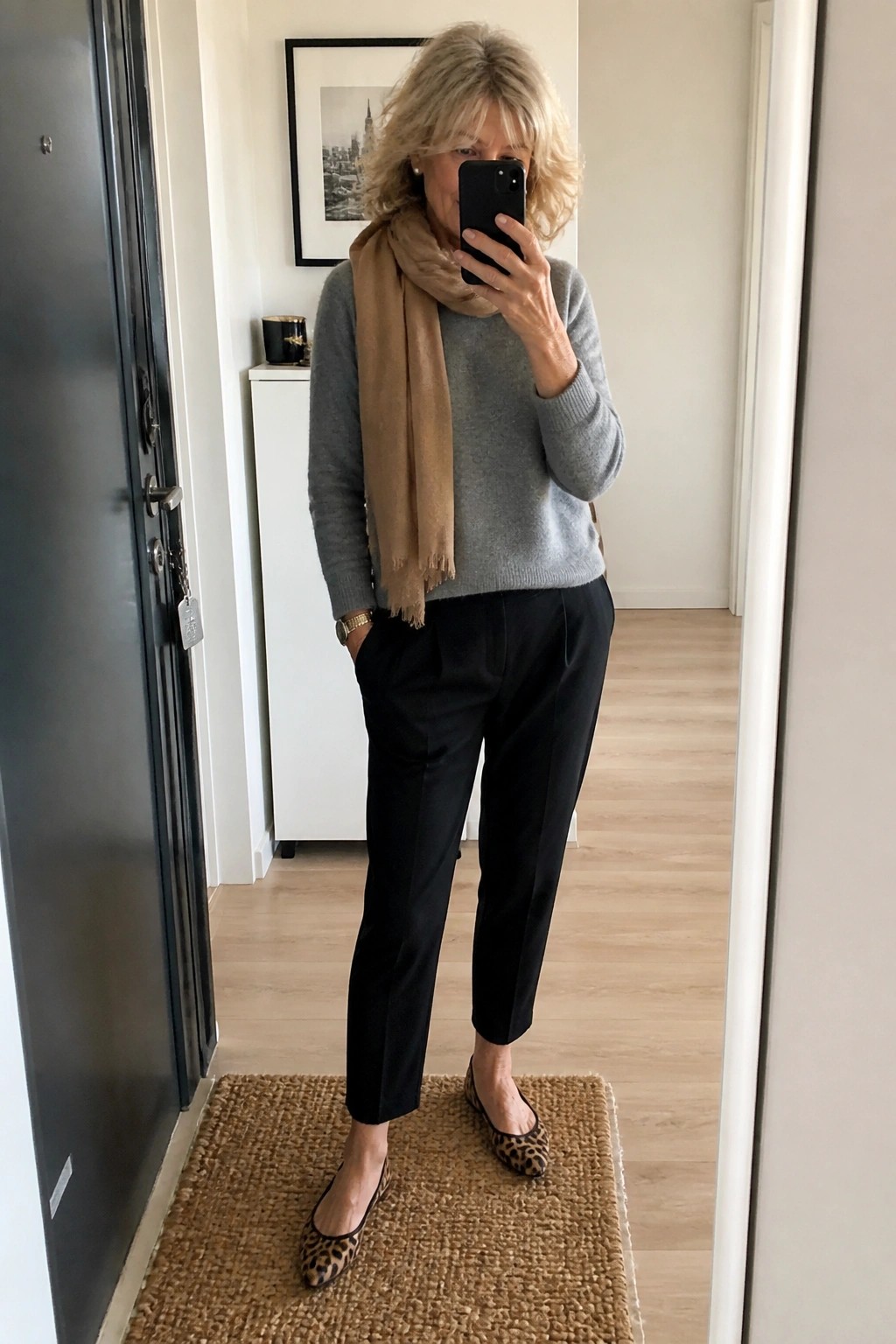 Woman in gray sweater, tan scarf, black pants, leopard flats taking mirror selfie