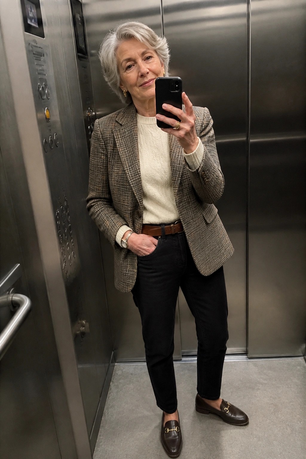 Gray-haired woman in plaid blazer taking phone selfie in elevator