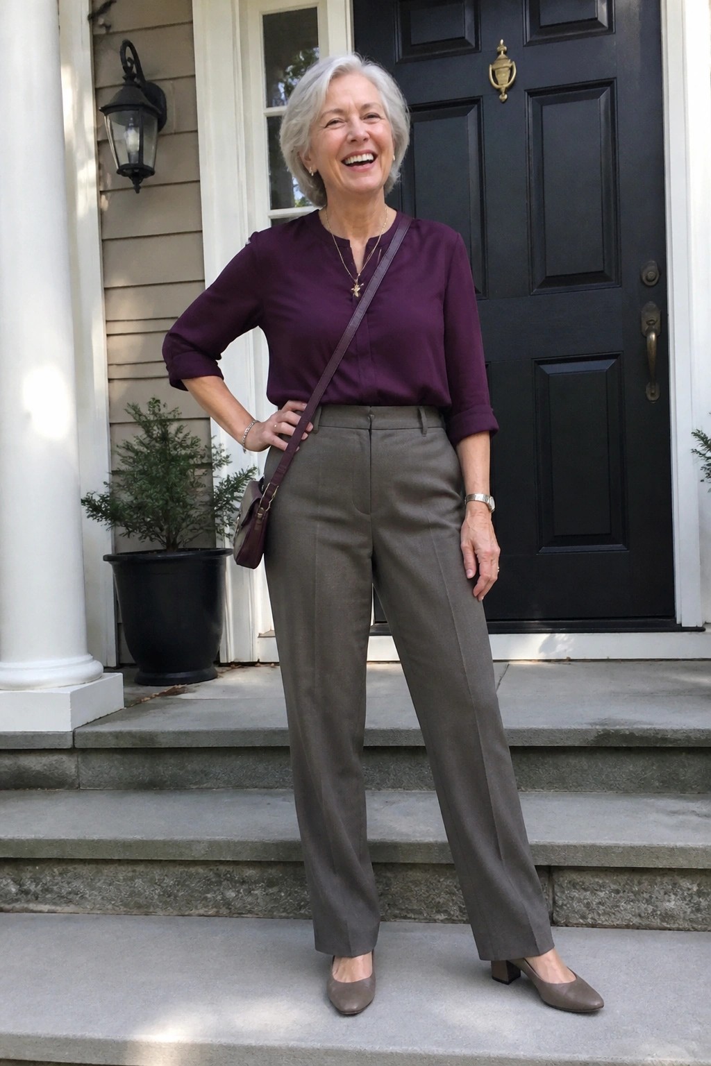 Smiling gray-haired woman in purple blouse and gray pants on porch steps