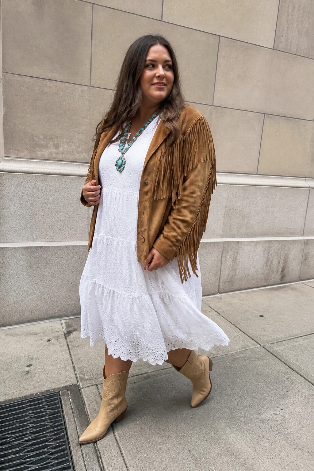 Woman in white lace dress, brown suede fringe jacket, turquoise necklace, and cowboy boots.