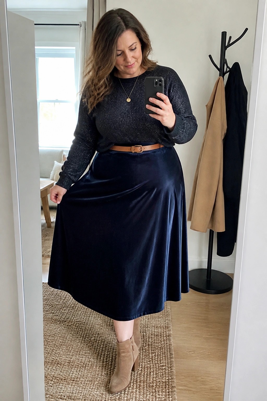Woman taking mirror selfie in sparkly top, navy velvet skirt, and ankle boots.