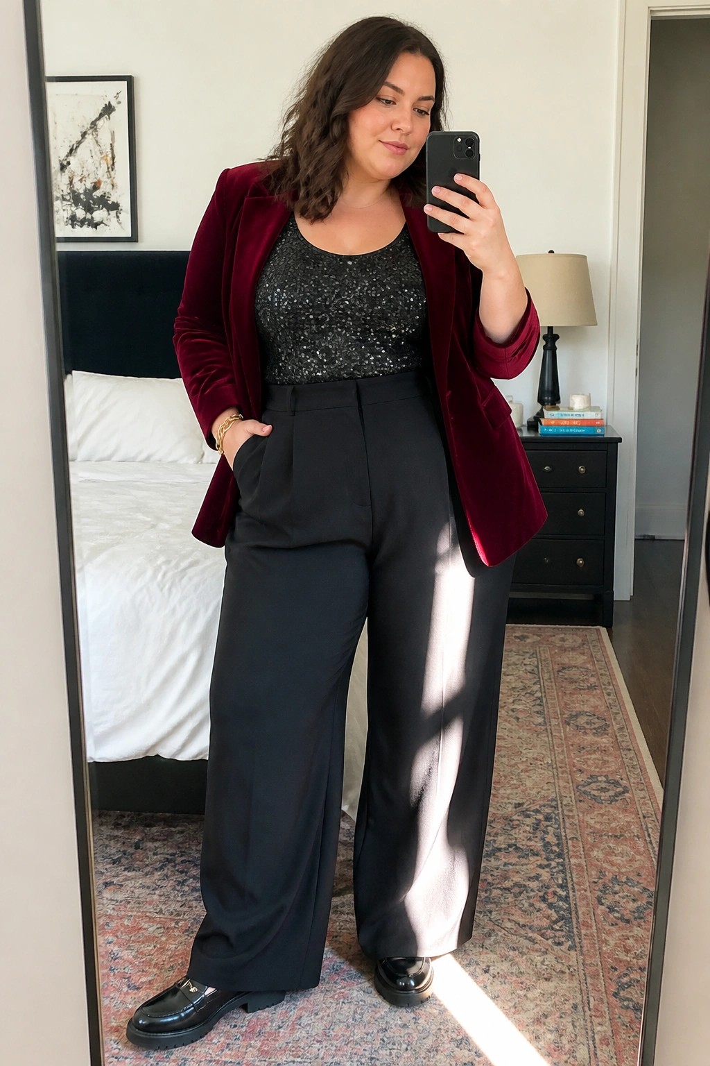 Woman in red velvet blazer and sequined top taking bedroom mirror selfie