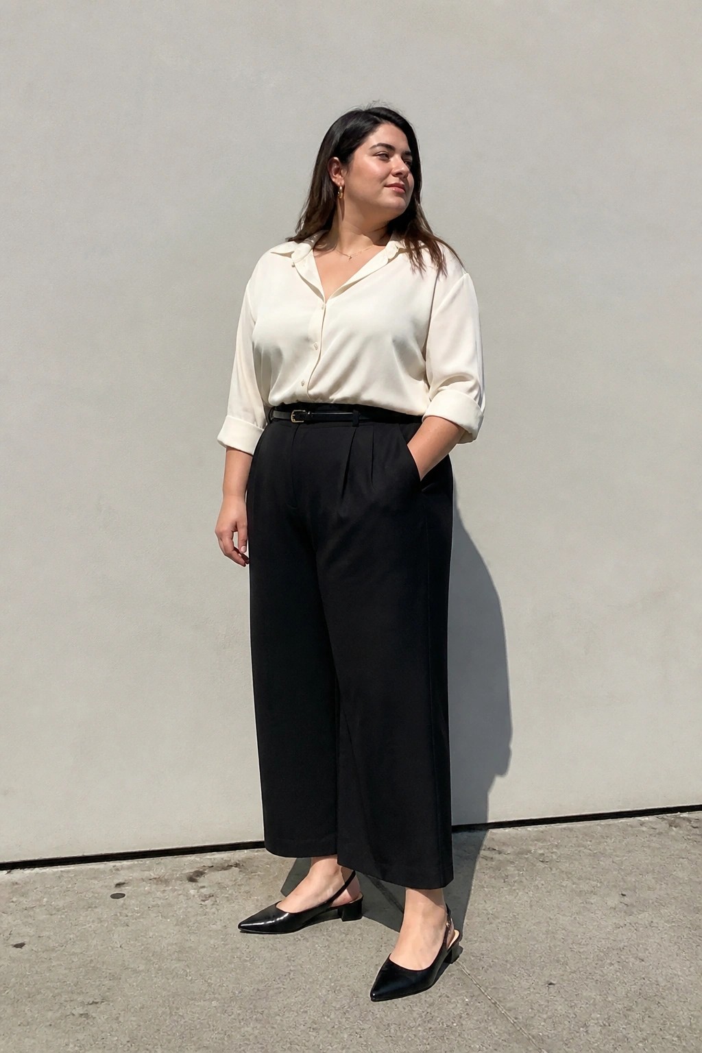 Woman in cream shirt and black wide-leg pants with black heels outdoors.