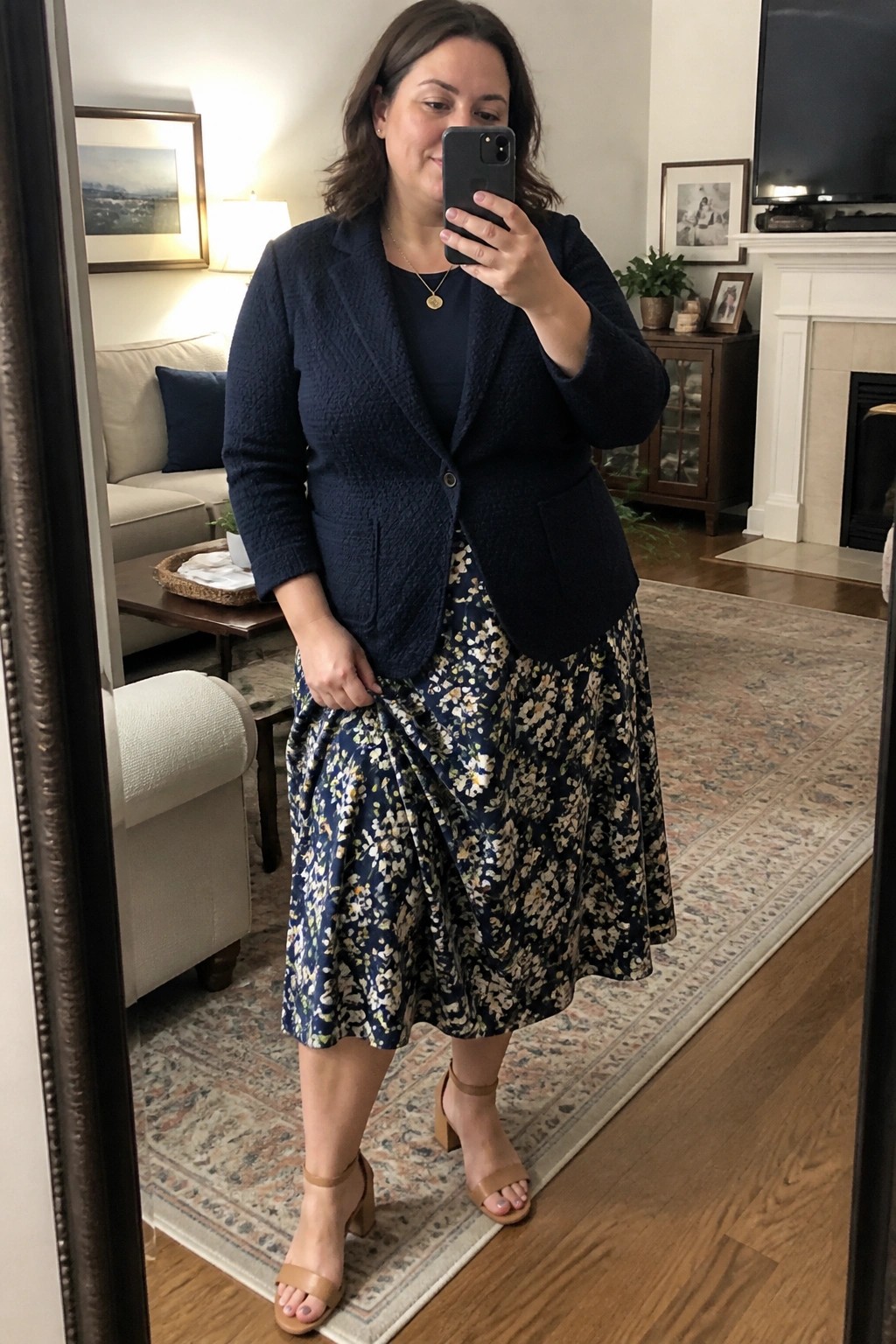 Woman wearing navy textured blazer over navy top with navy floral midi skirt and tan block heel sandals in mirror selfie pose.