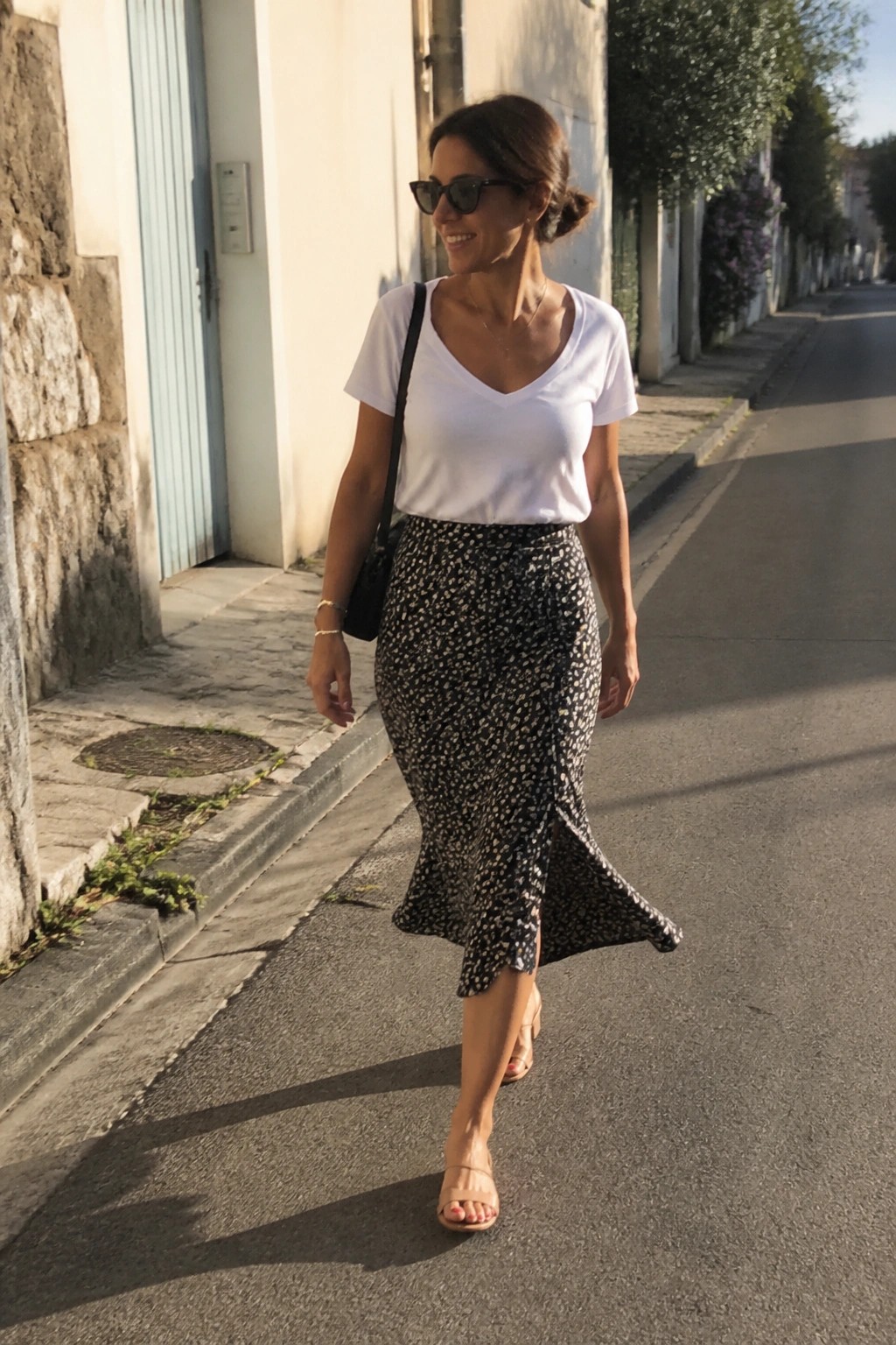 Woman in white top and floral skirt walks on sunny street