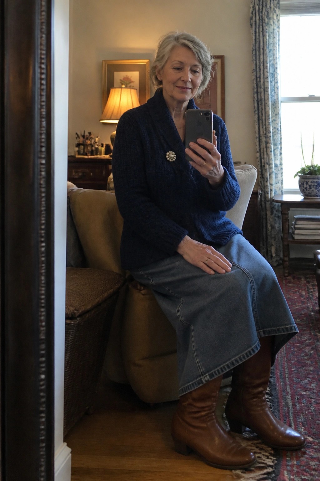 Older woman in blue knit cardigan and denim skirt taking mirror selfie in living room
