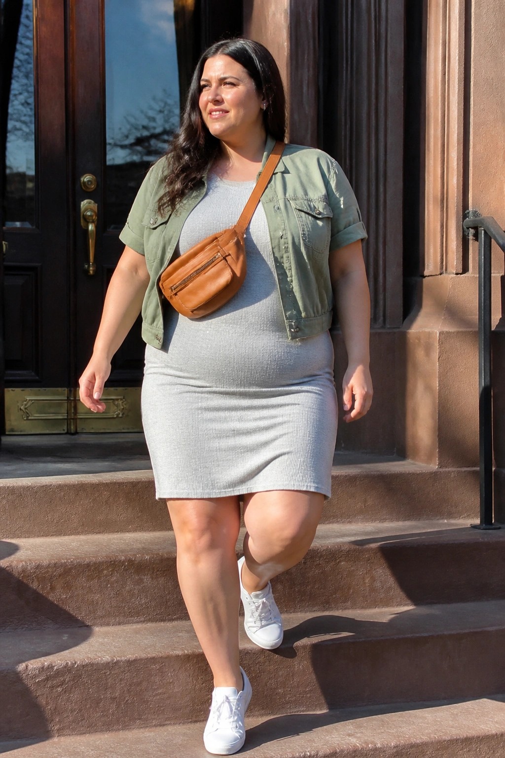 Woman in gray dress and green jacket on brownstone steps with brown bag