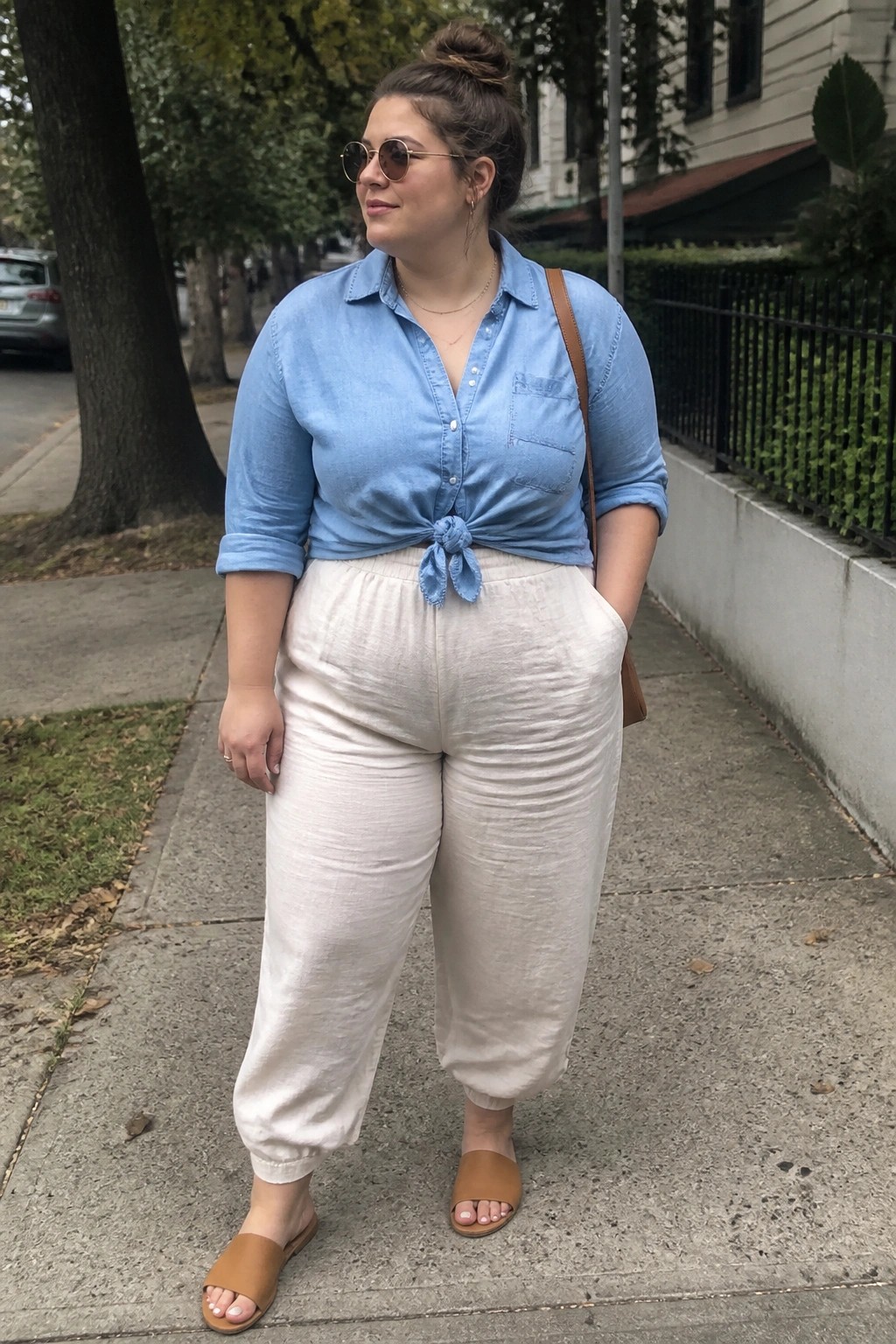 Woman in light blue tied shirt and white pants on sidewalk
