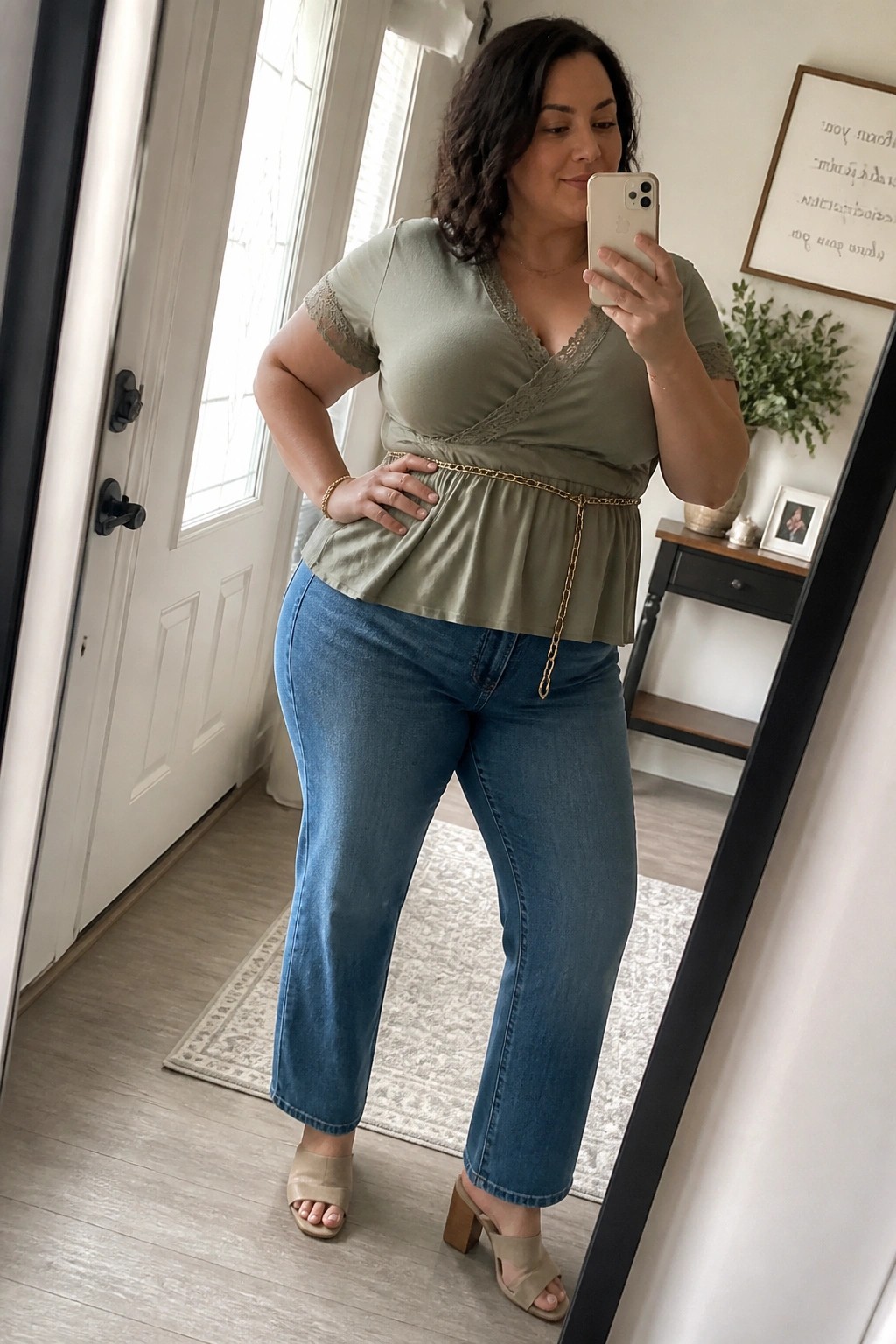 Woman in sage green lace top and blue jeans taking mirror selfie