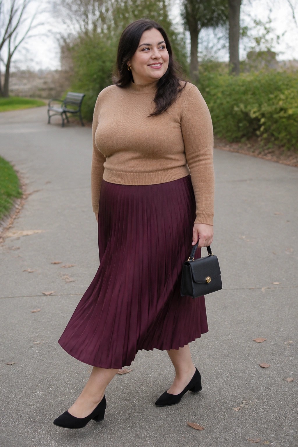 Plus size woman in tan ribbed turtleneck sweater tucked into burgundy pleated midi skirt, paired with black block heel pumps and small black handbag.