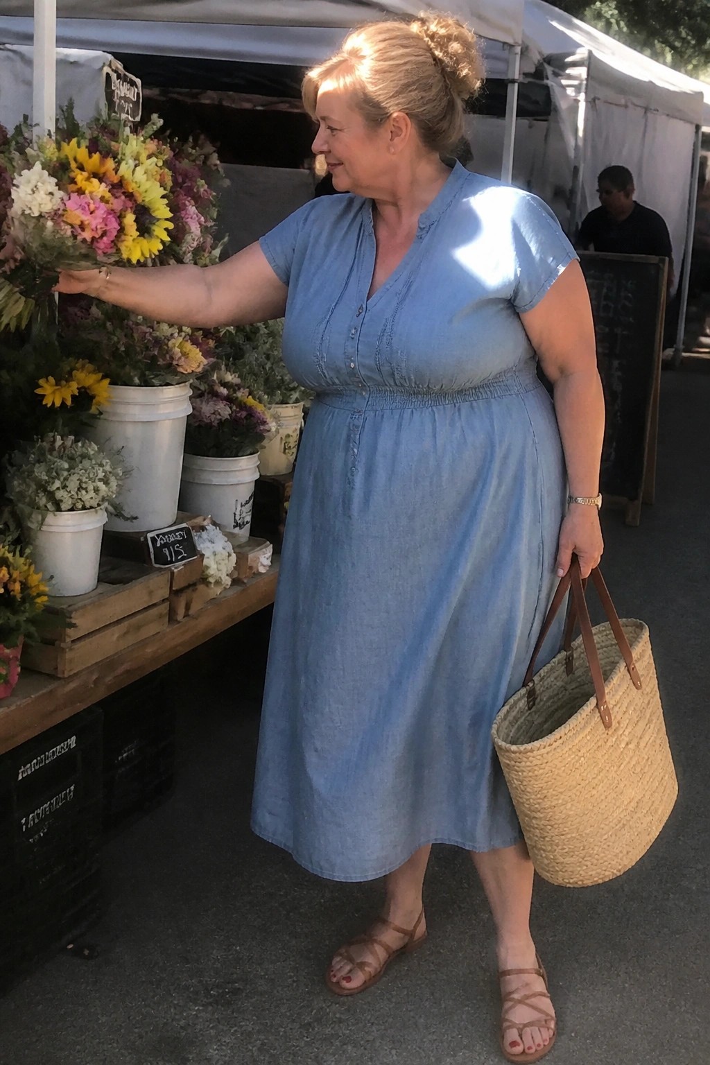 Woman in light blue denim dress holds straw tote at flower market