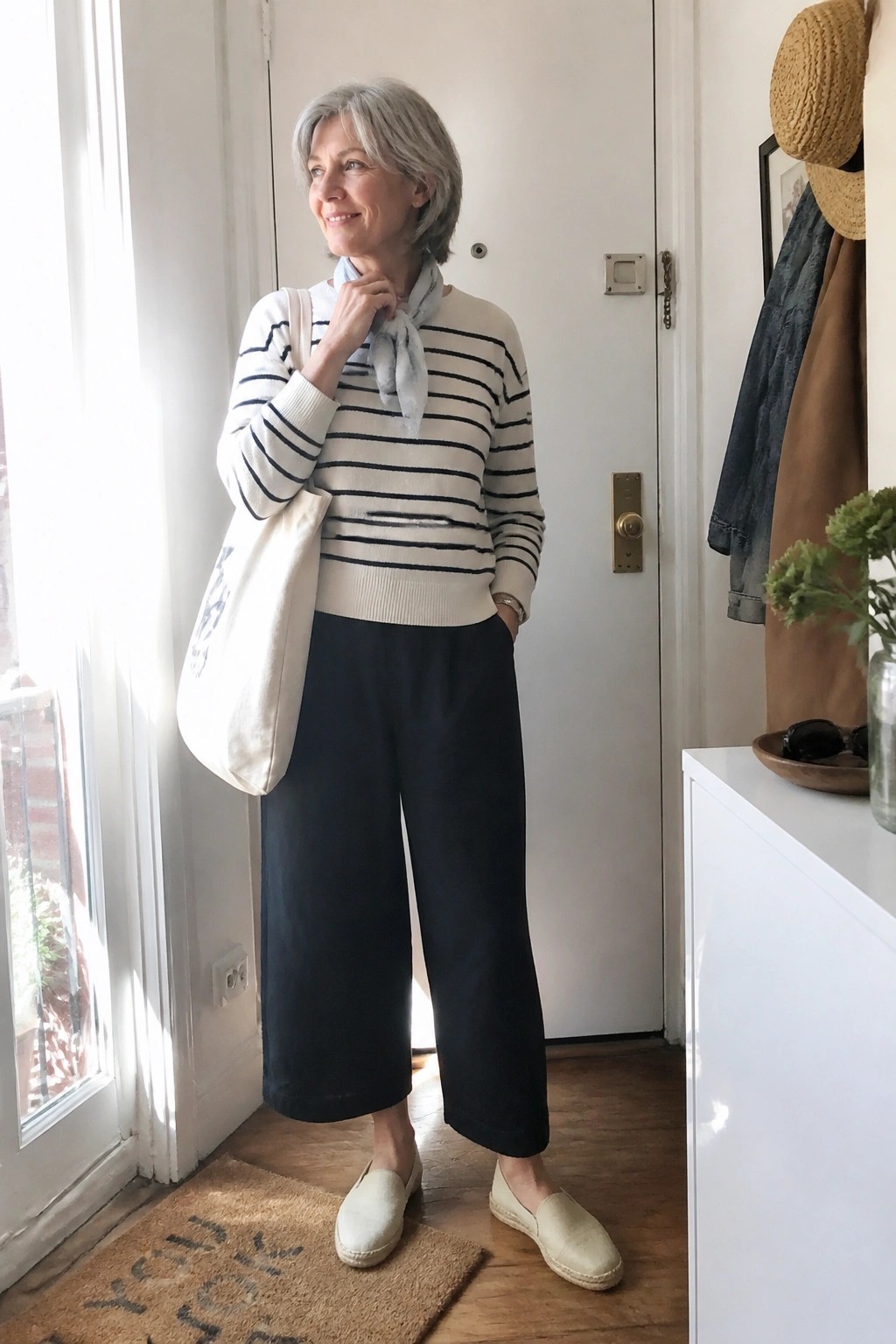 Smiling woman in striped sweater, black culottes, and espadrilles with tote bag