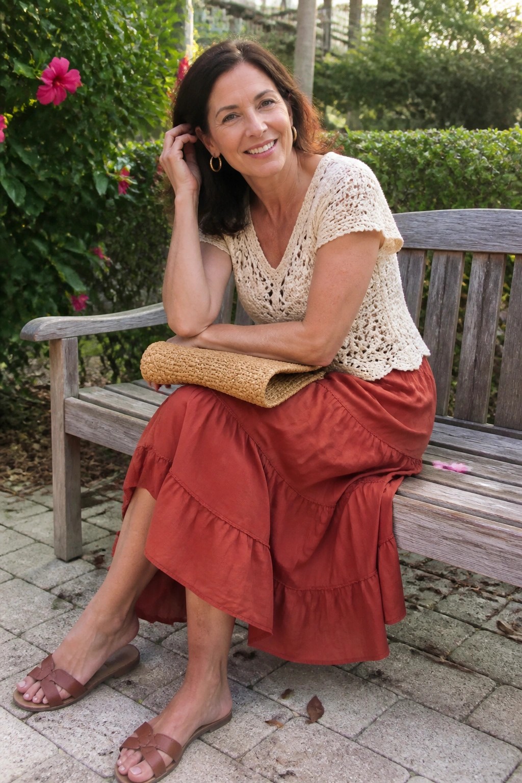Smiling woman in crocheted top and tiered red skirt on wooden garden bench