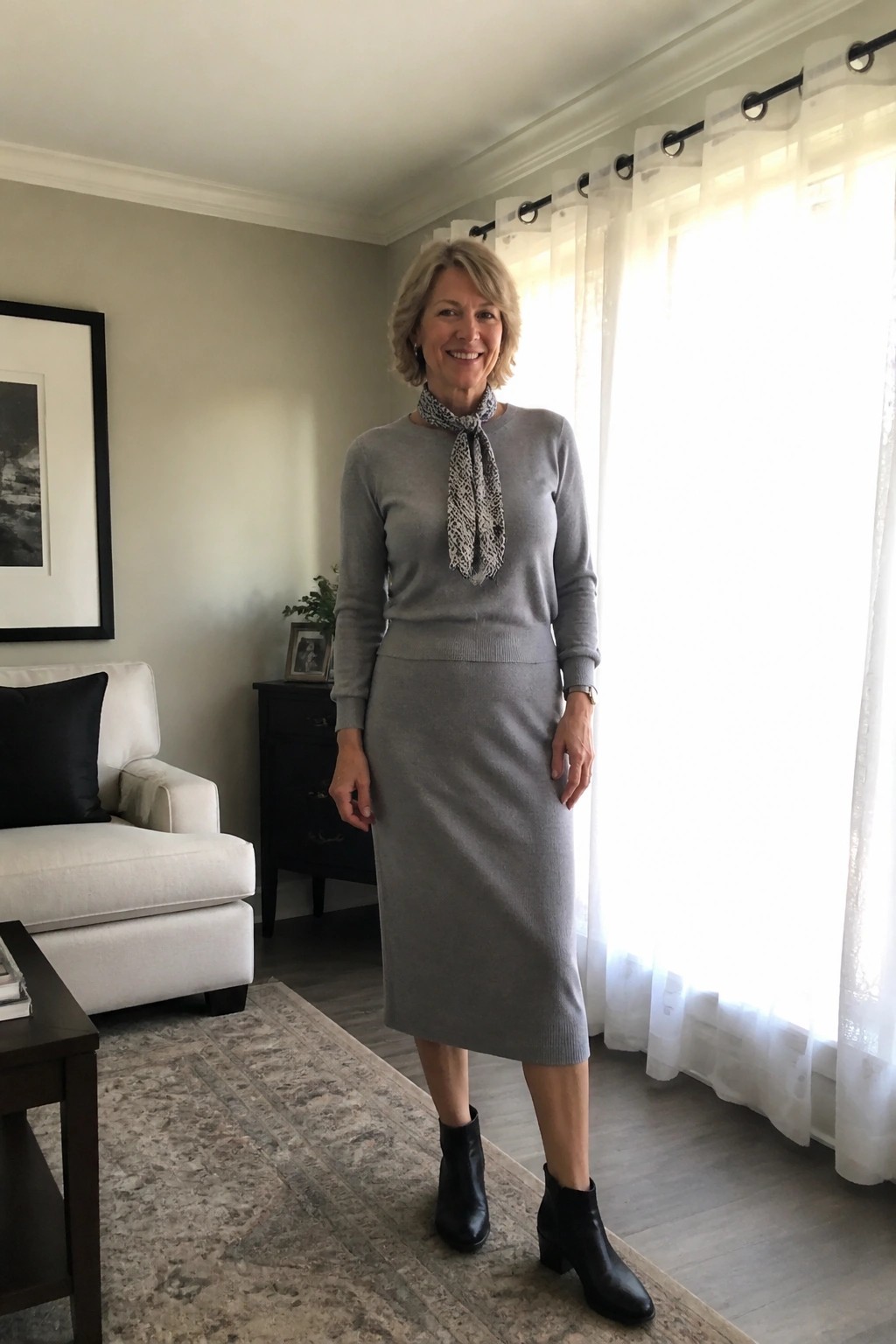 Woman in gray sweater and skirt with patterned scarf standing in bright living room