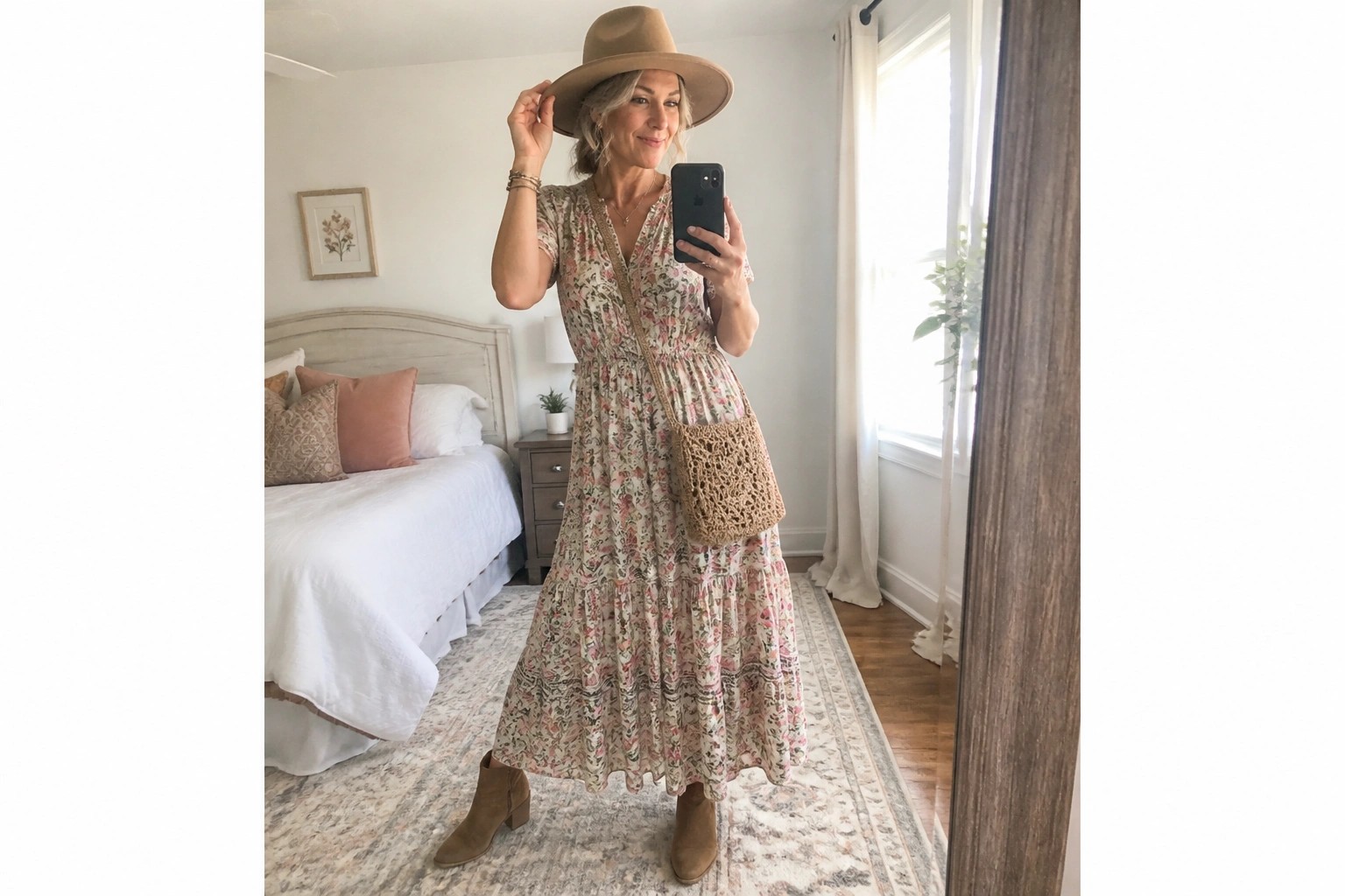 Woman in floral maxi dress and hat taking bedroom mirror selfie
