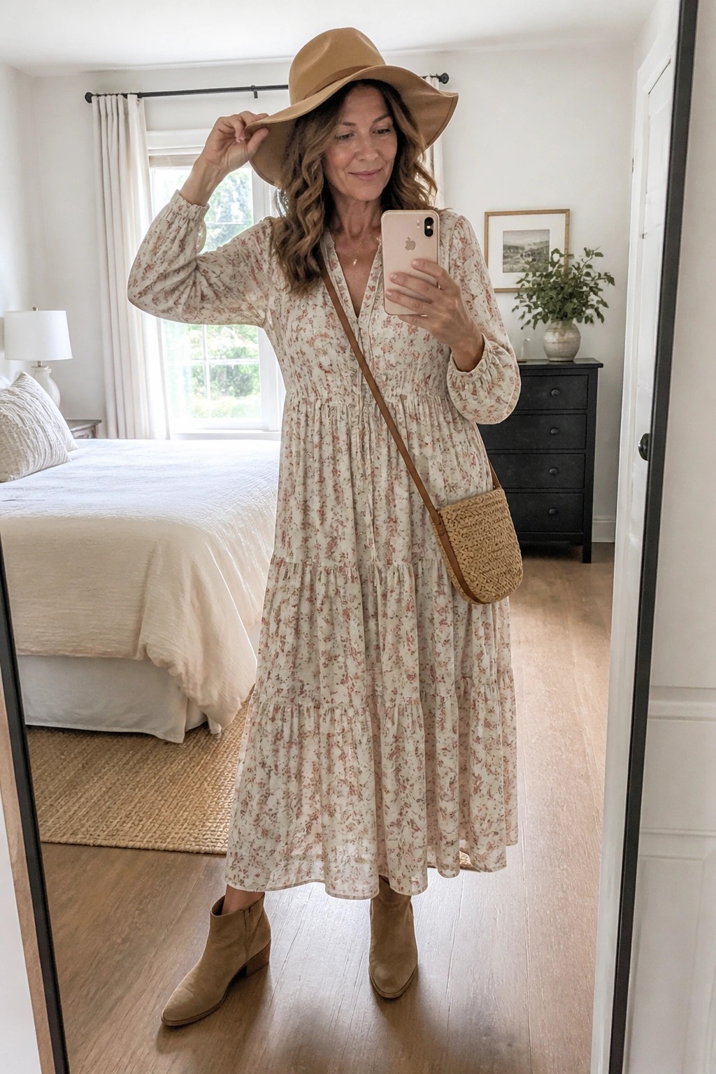 Woman in floral maxi dress and hat taking bedroom mirror selfie