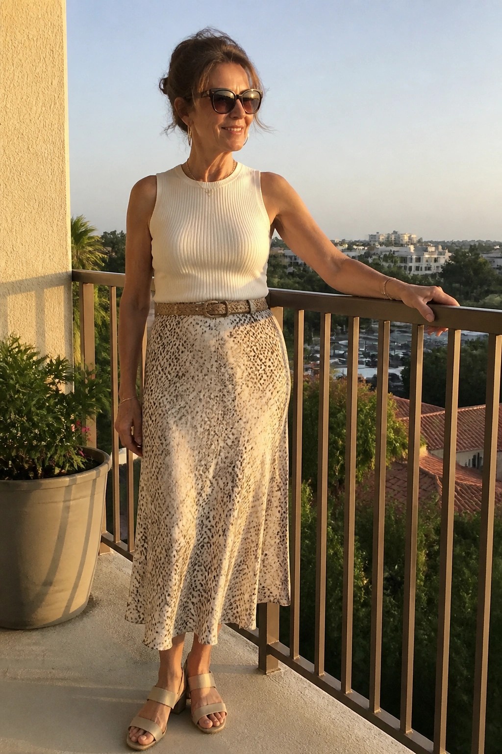 Woman in white ribbed top and leopard-print skirt on sunny balcony railing