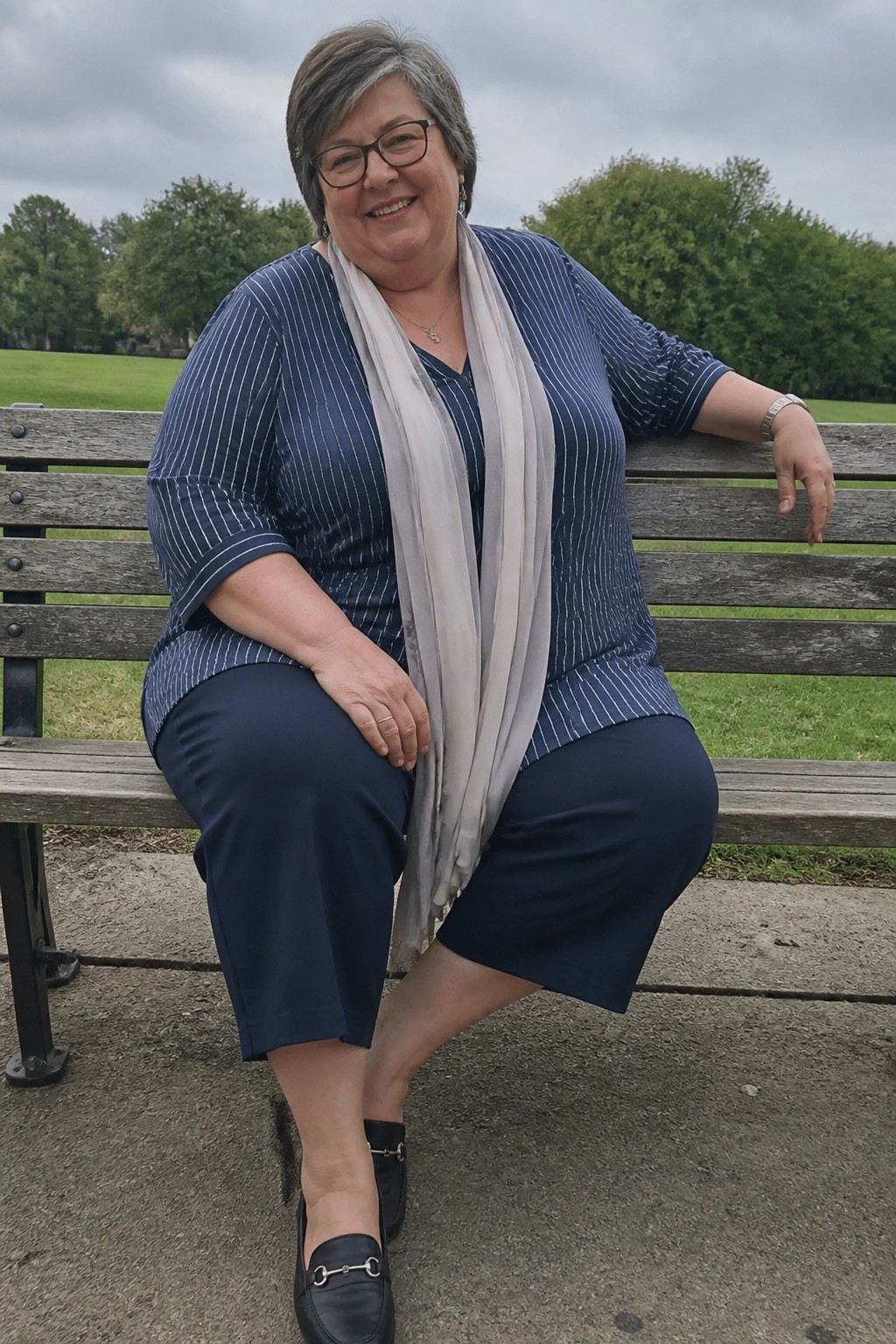Smiling woman in blue striped top with gray scarf on wooden park bench