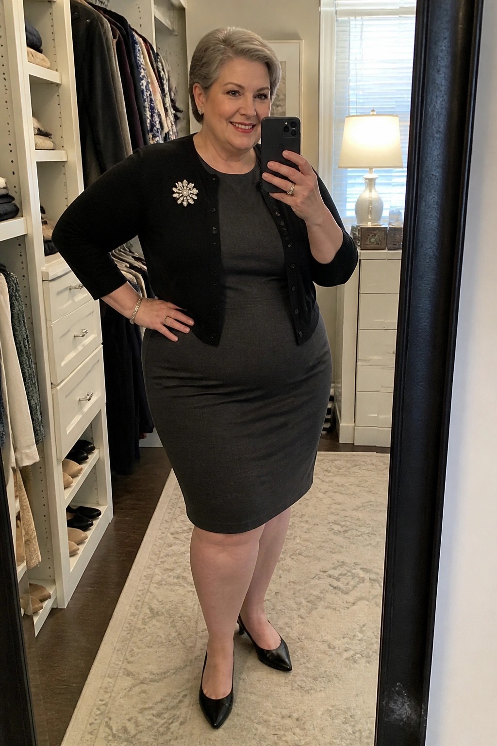 Woman in gray dress and black cardigan with snowflake brooch taking closet mirror selfie