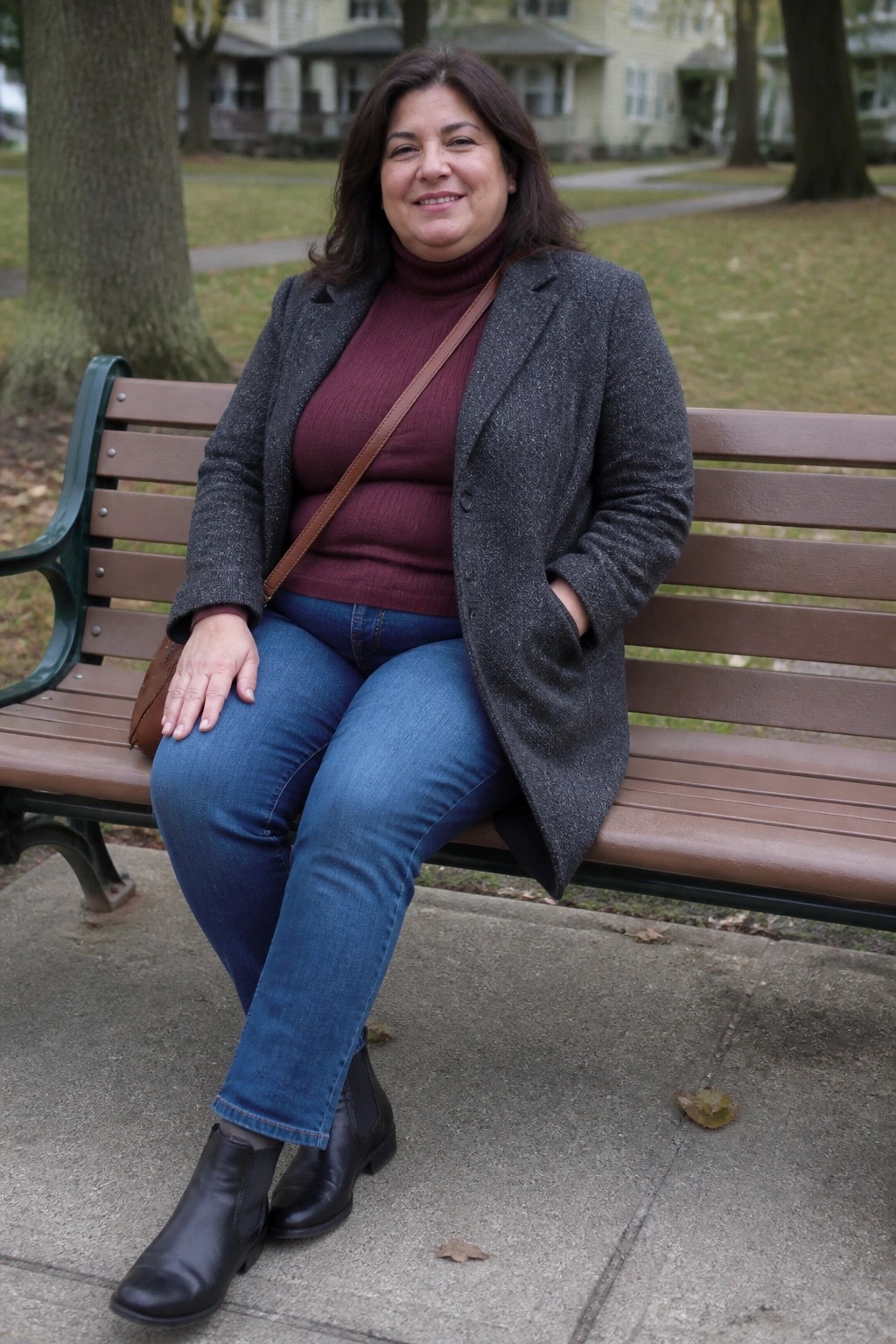 Smiling woman in maroon turtleneck and gray coat on park bench
