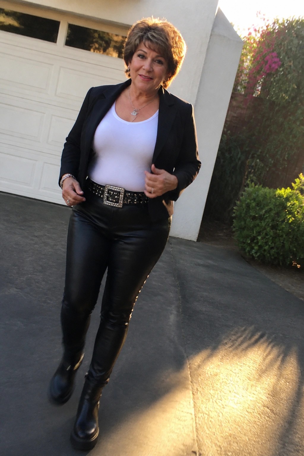 Woman in black blazer and leather pants with studded belt outside garage door